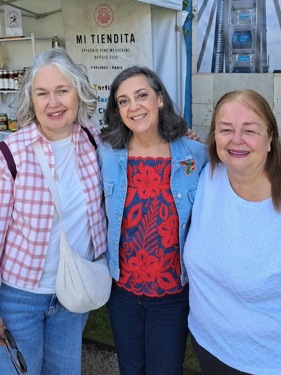 Trois femmes souriantes devant le stand Mi Tiendita